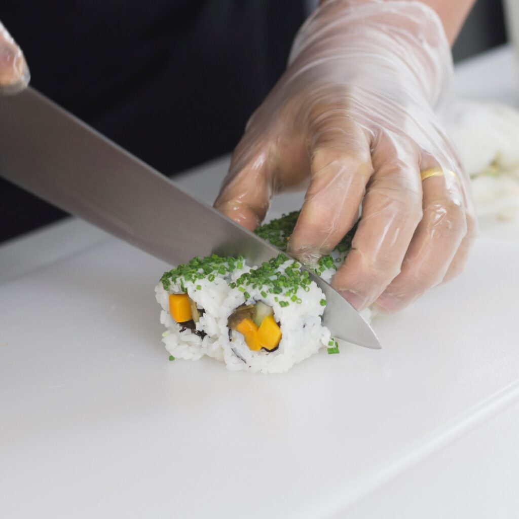 A sushi chef carefully slices uramaki rolls during a sushi masterclass.